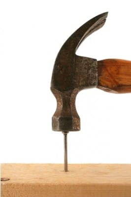 A hammer pounding a nail in wood